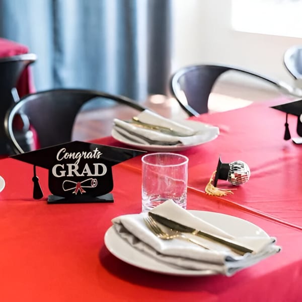 A red table set for a graduation party with "Congrats GRAD" decor and place settings.