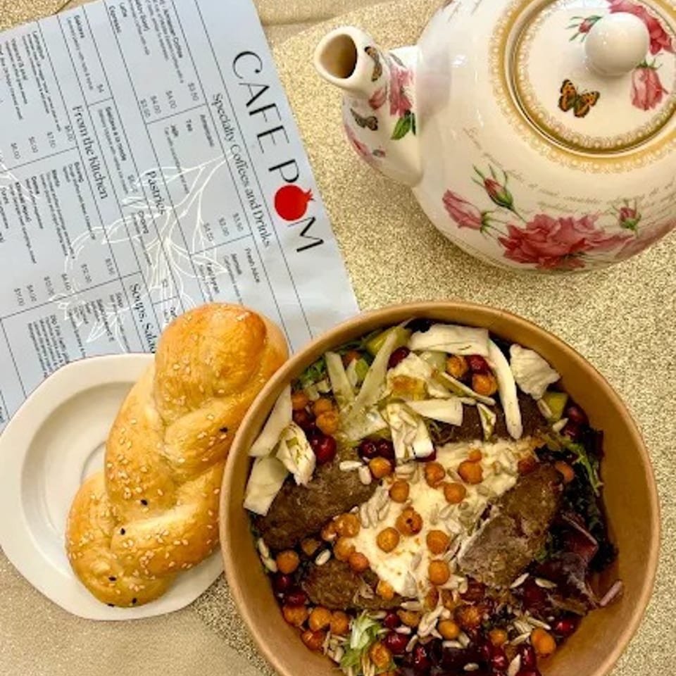 Cafe POM menu, a Mediterranean salad with chickpeas and meat, braided bread, and a floral teapot.