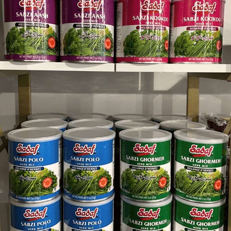 Shelves filled with Sadaf brand Sabzi Aash, Kookoo, Polo, and Ghormeh herb mix cans.
