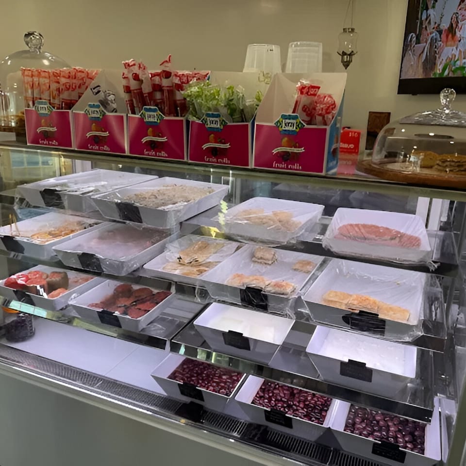 A refrigerated display case at Cafe POM filled with various Mediterranean dishes and ingredients.