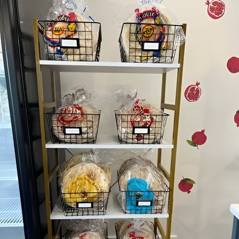 Baskets of pita bread on white shelves with pomegranate decorations on the wall at Cafe POM.